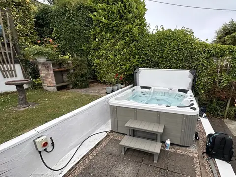 Hot tub with its cover off in a walled garden, with steps up to it