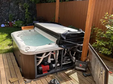 Hot tub on a garden deck with its cabinet open and the pump showing