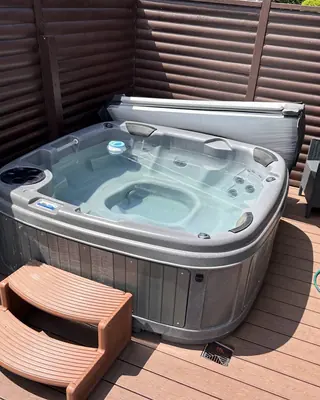 Grey hot tub on a timber deck, with steps up to it
