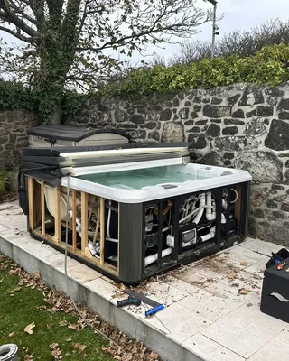 Hot tub against an old stone wall with its cabinet panels removed for repair